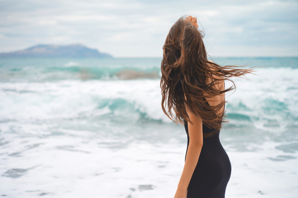 Beautiful young woman walking at the sea - Фото, изображение