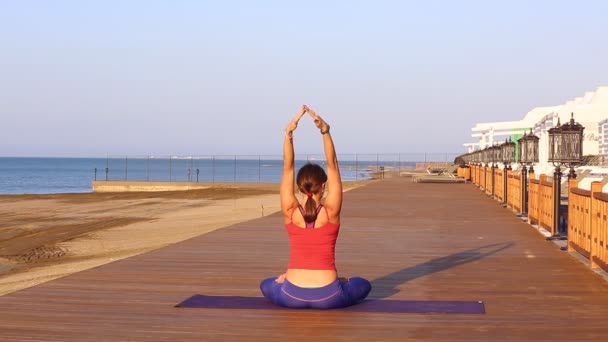 Jolie femme qui fait du yoga sur la plage. Femme sportive assise en position de yoga sur fond de vue mer
. - Séquence, vidéo