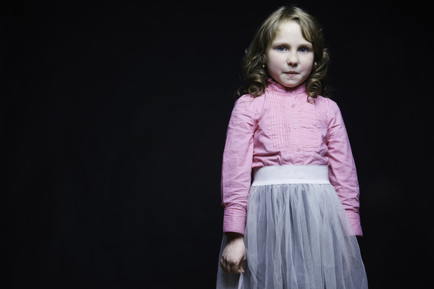 Beautiful little girl in a pink blouse and white skirt on a black textured background - Valokuva, kuva