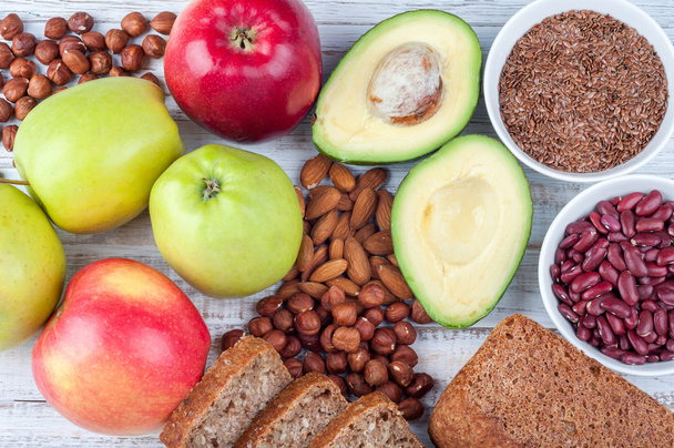 Здоровое питание - избегадо, семена льна, цельнозерновой хлеб, орехи и яблоки на деревянном фоне
 - Фото, изображение