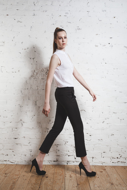 fashion model in black trousers and white blouse posing over whi - Foto, afbeelding
