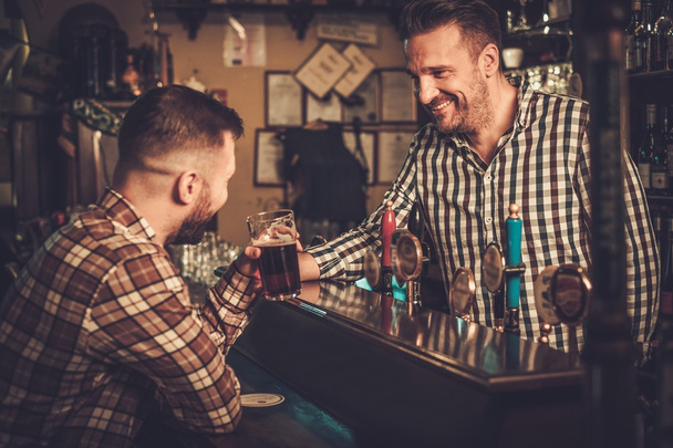Camarero guapo sirviendo una pinta de cerveza al cliente en un pub
. - Foto, Imagen