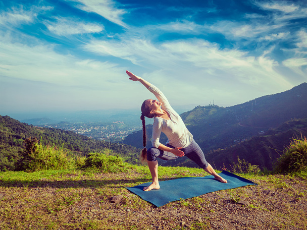 Женщина практикует йогу как Уттхита Парсваконасана на открытом воздухе - Фото, изображение