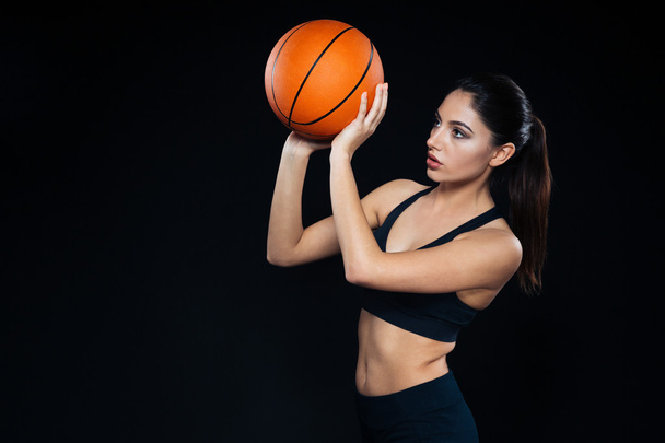 Focused pretty woman athlete standing and throwing basketball ball  - Photo, image