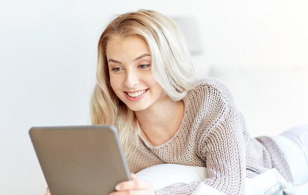 happy young woman with tablet pc in bed at home - Foto, afbeelding