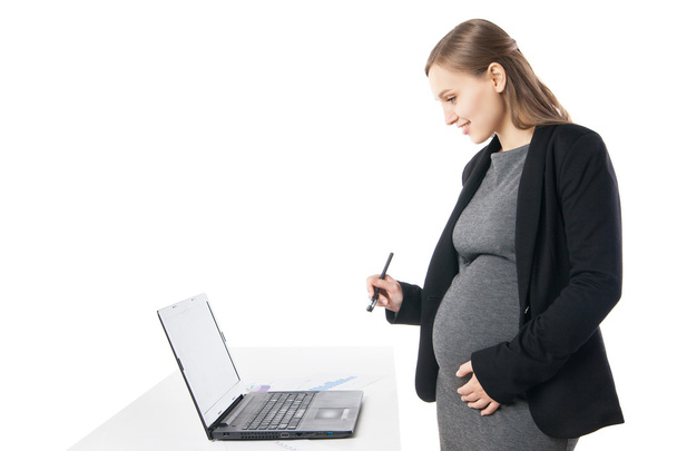 Femme d'affaires enceinte souriant tout en travaillant sur ordinateur portable
 - Photo, image