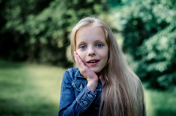 Verbaasd schattig klein blond meisje bij zomer veld. - Foto, afbeelding
