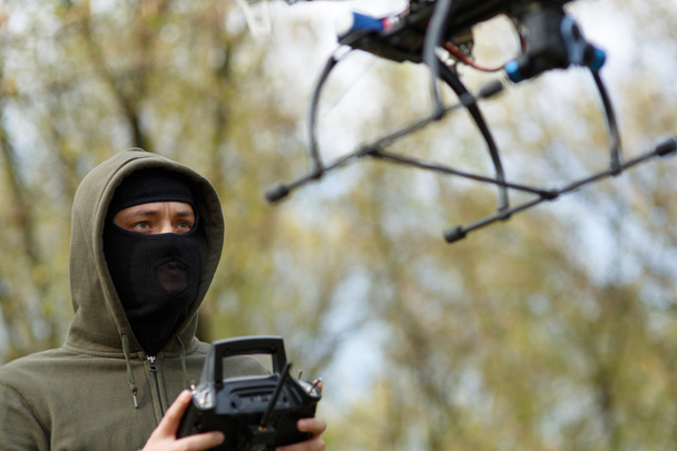 Man in mask operating a drone with remote control. - Фото, зображення