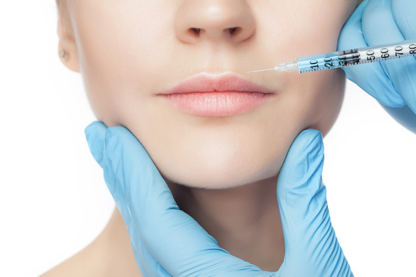 Attractive woman at plastic surgery with syringe in her face - 写真・画像