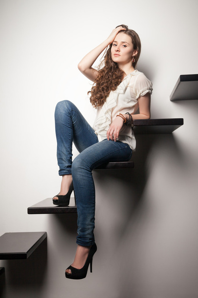 Portrait of brunette sitting on steps in wall - Foto, Imagen