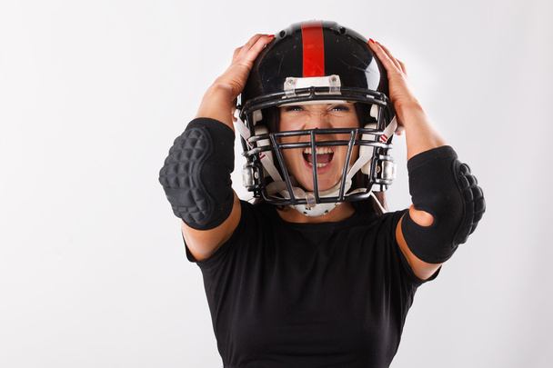 Young woman with football helmet and protection suit on a white background.American Football player girl - Foto, imagen