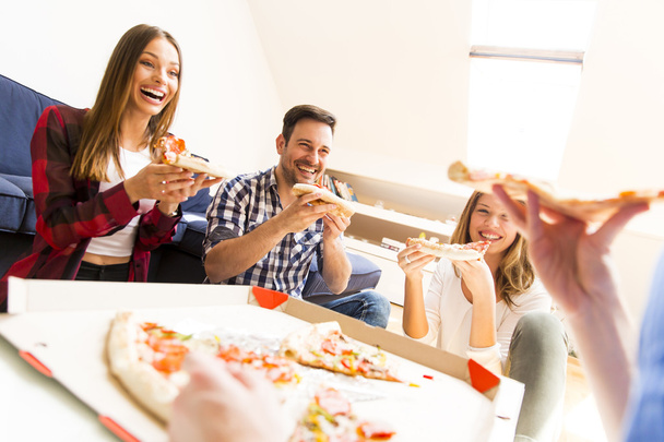 Молодые люди едят пиццу в комнате
 - Фото, изображение