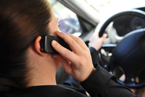 νεαρή γυναίκα σε ένα αυτοκίνητο που μιλάμε για ένα κινητό τηλέφωνο - Φωτογραφία, εικόνα