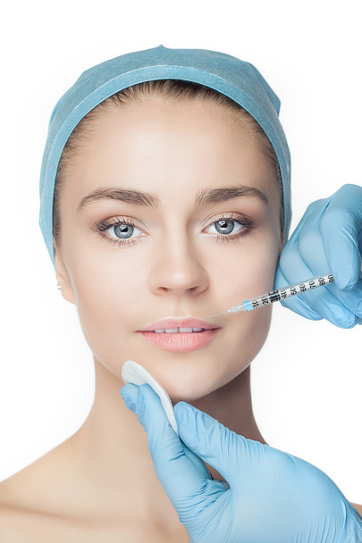Attractive woman at plastic surgery with syringe in her face - Foto, imagen
