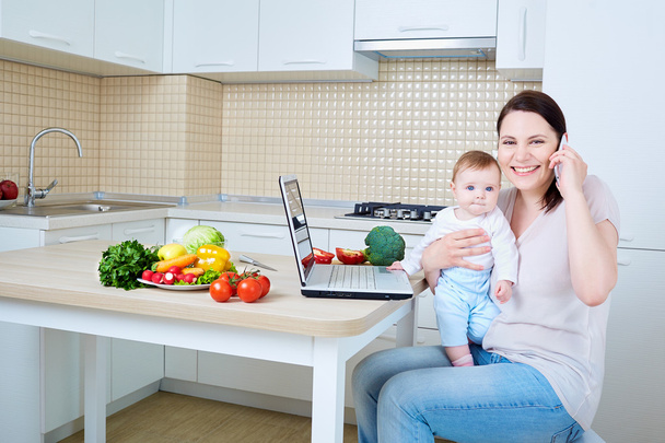 Woman with child preparing food and talking on the phone.Happy f - Photo, image