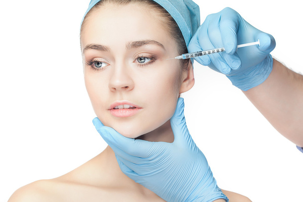 Attractive woman at plastic surgery with syringe in her face - Foto, imagen