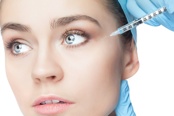 Attractive woman at plastic surgery with syringe in her face - Fotoğraf, Görsel