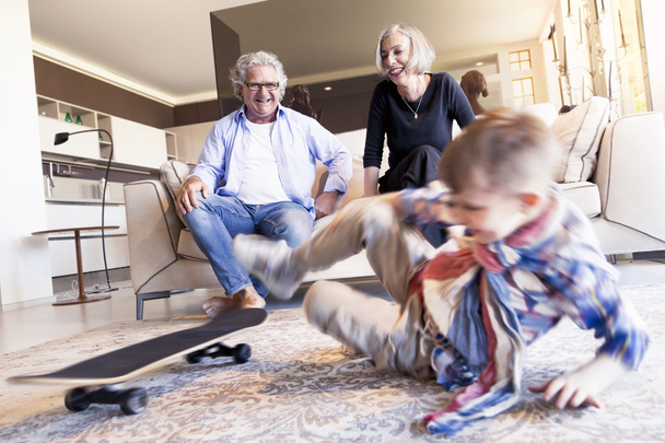 couple of happy grandparents are fun nephew with skateboard - Foto, afbeelding
