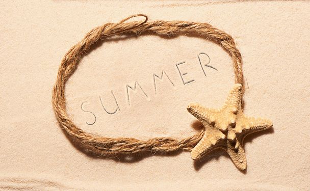 Marco de cuerda con letras de estrellas de mar y de verano sobre arena
 - Foto, Imagen
