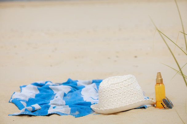 Ranta asettaa hattu ja aurinkovoidetta makaa hiekalla
 - Valokuva, kuva
