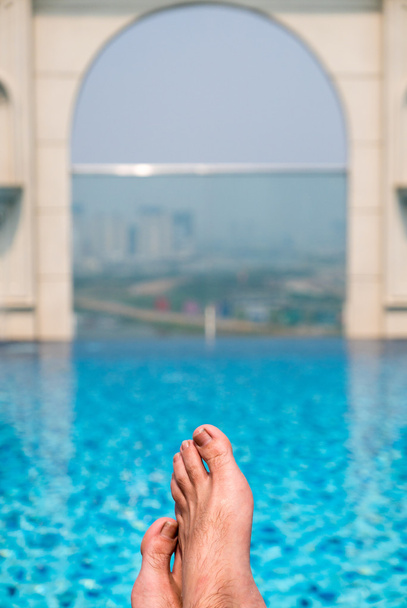 Feet over the sparkling pool on top of building with Saigon aeri - Photo, Image