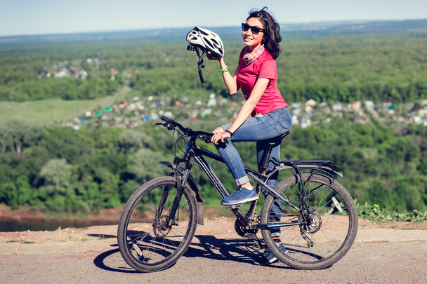 Pyöräilykypärä - nainen laittaa pyöräilykypärän pyörän ajon aikana
 - Valokuva, kuva