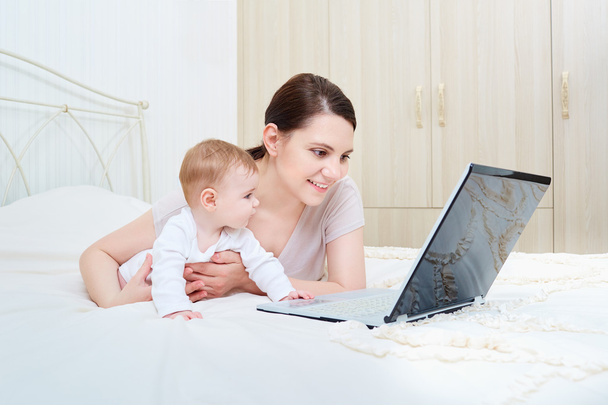 Mom and baby looking at a laptop and smiling happy. - Valokuva, kuva
