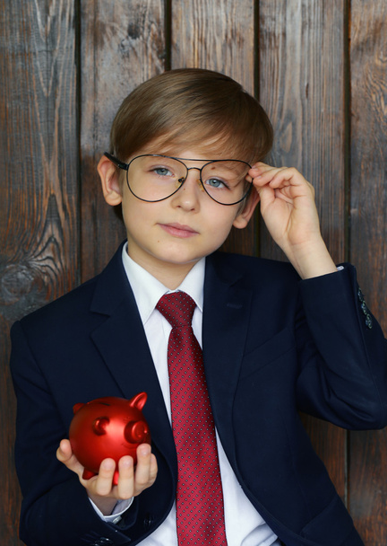 Niño en un traje con una alcancía roja - concepto de negocio
  - Foto, imagen