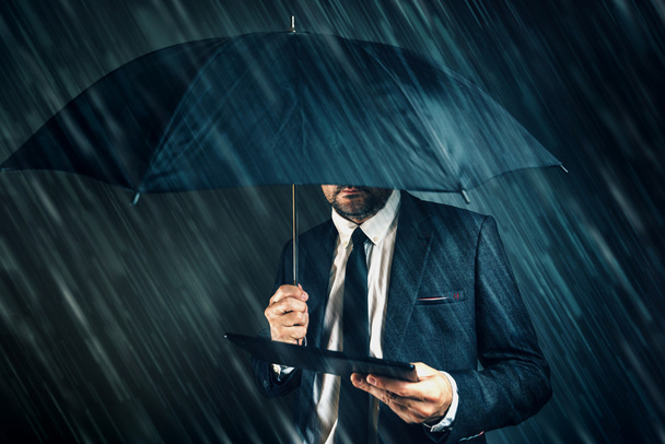 Businessman reading business news on digital tablet in rain - Foto, Imagem