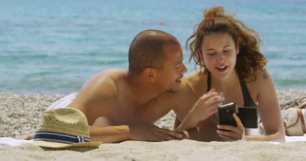 couple relaxing at the beach with a cell phone - Materiaali, video