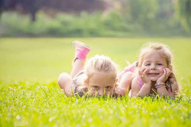blonde lachende zus spelen in een tuin - Foto, afbeelding