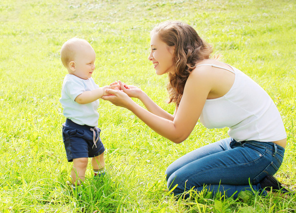 Happy mother playing with baby on grass in summer day - Fotografie, Obrázek
