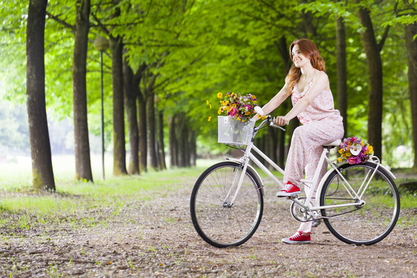 woman standing with a vintage bicycle at the park - Foto, afbeelding