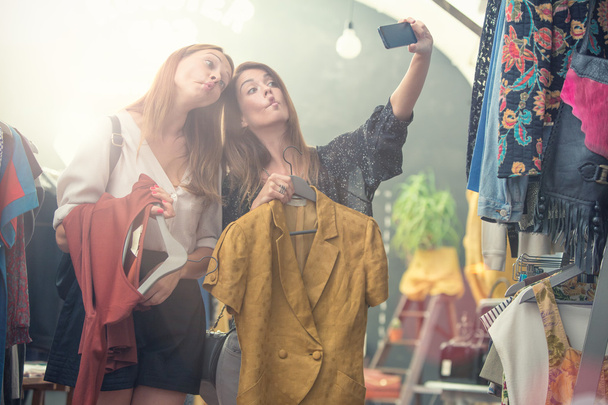 dwóch uśmiechniętych przyjaciół cieszyć się w sklepie odzieżowym - Zdjęcie, obraz