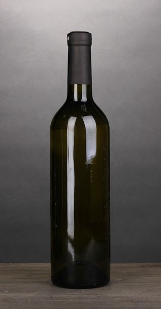 Bottle of great wine on wooden table on grey background - Фото, изображение