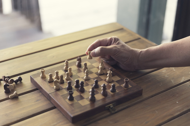 mano que sostiene el peón del juego del tablero de ajedrez en la tabla de madera, vintage a
 - Foto, Imagen