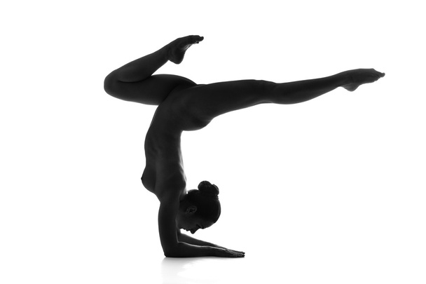 Nude yoga. Artistic photos of beautiful sexy body of young woman with perfect figure. Vrischikasana or scorpion pose. Isolated on white background - Fotoğraf, Görsel