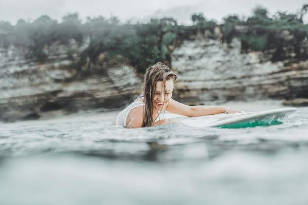 mooi meisje in de oceaan Surf in de regen - Foto, afbeelding