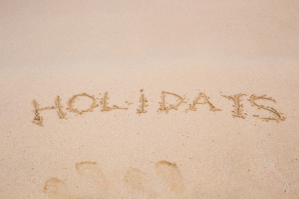 Słowo wakacje odręcznie na piaszczystej plaży na tropikalnej wyspie - Zdjęcie, obraz