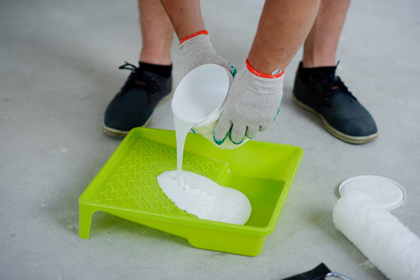 The person pours white paint in a tray. - 写真・画像