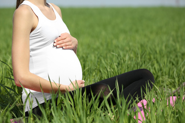 Pregnant woman relaxing in field - Foto, immagini