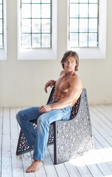 Suntanned mannelijk model ontspannen op een stoel. - Foto, afbeelding