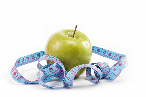 Natural products. Diet. Fresh apple with a measuring tape on a w - Photo, Image