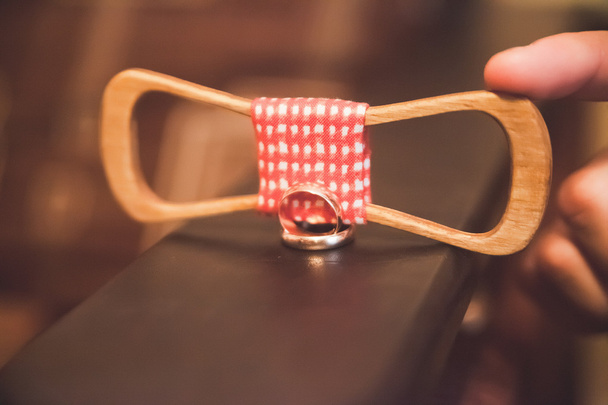 a wooden bow tie and two wedding rings on a wooden stand - 写真・画像