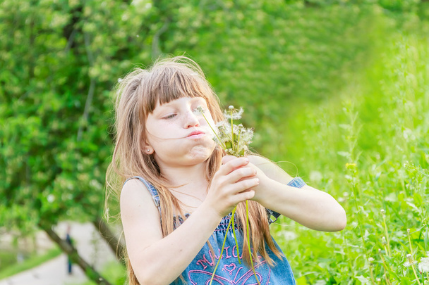 Hermosa niña con flor de diente de león en el parque de primavera. Feliz.
 - Foto, Imagen