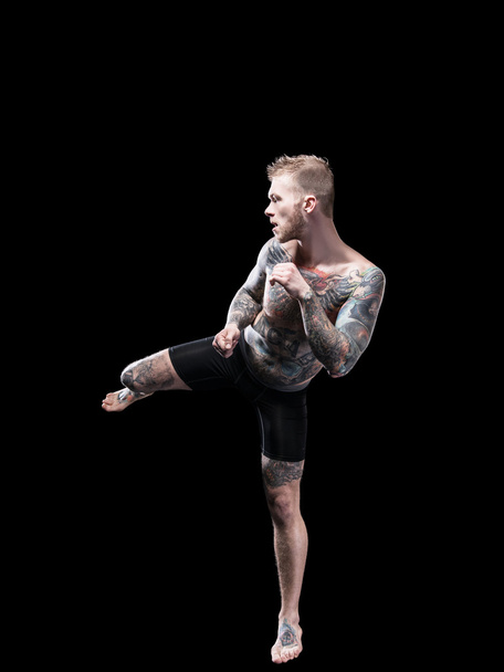 Strong mma fighter prepared high kick on black background - Photo, Image
