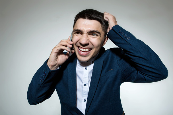 Puzzled businessman talking on the phone and scratching head - Φωτογραφία, εικόνα
