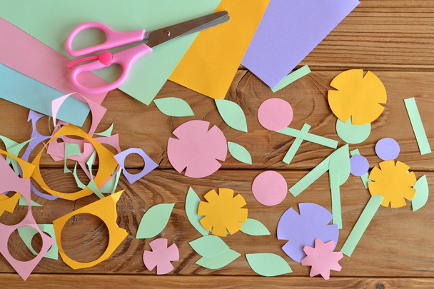 Artisanat de fleurs en papier pour enfants. Fleurs en papier, feuilles de papier, ciseaux, débris de papier sur une table en bois. Projet artistique pour enfants - Photo, image