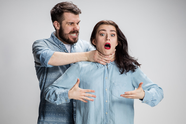 The quarrel men and women. Man strangling a woman on gray background - Valokuva, kuva