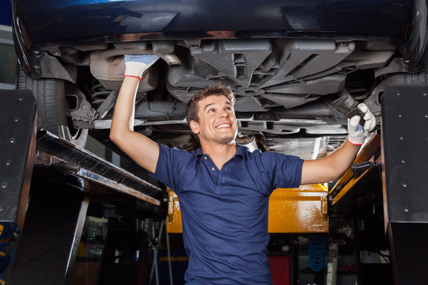 Mechanic Examining Underbeneath Lifted Car
 - Фото, изображение
